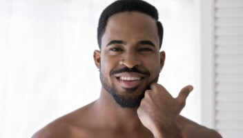 Man smiling and touching his face)